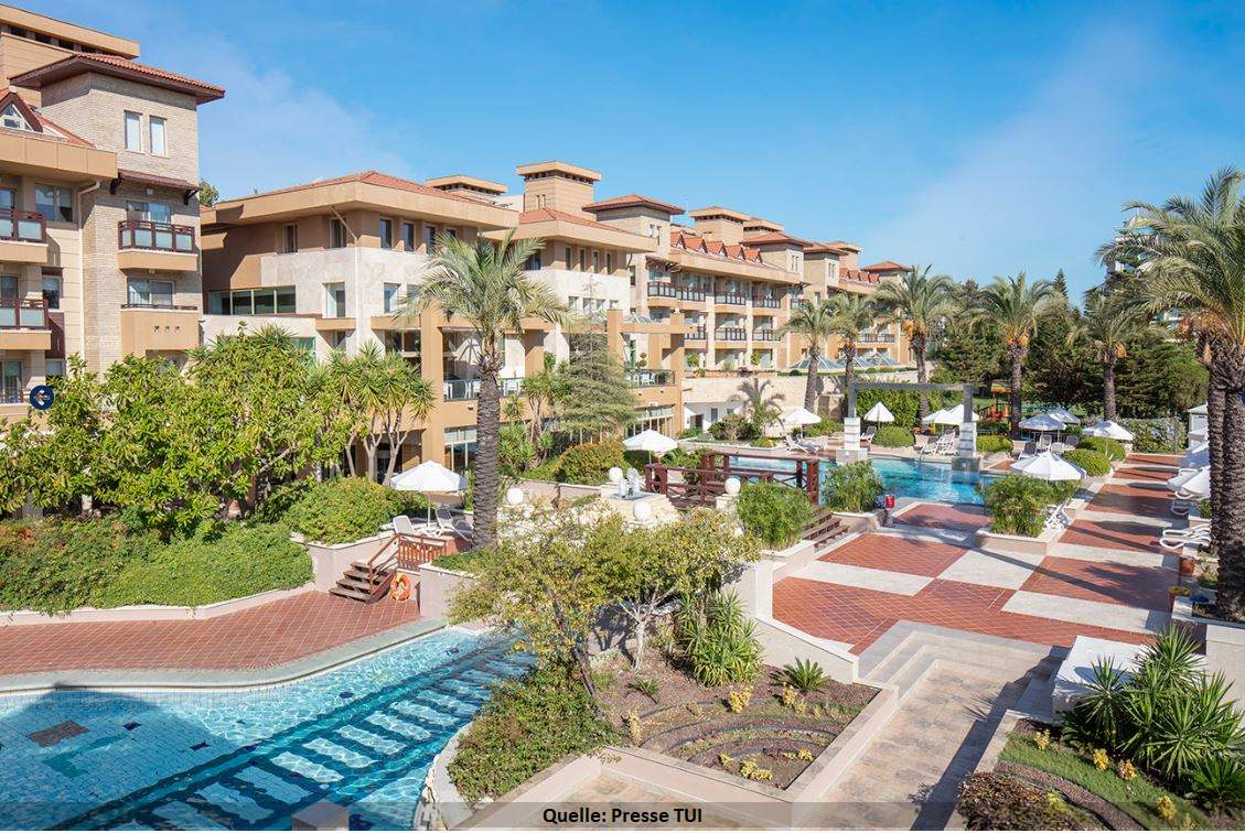Das Hotel TUI Blue Xanthe an der türkischen Riviera. Blick auf das Hotel. Im Vordergrund eine weitläufige Gartenanlage mit Palmen. Der Pool schlängelt sich wie ein Flußlauf durch die Anlage.