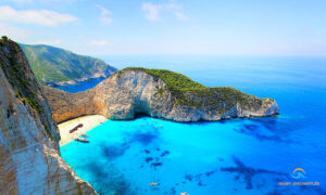 Das Schiffswrack von Zakynthos aus der Luft. Es liegt am Strand einer kleinen Bucht umgeben von Bergen.Das Meer ist blau.