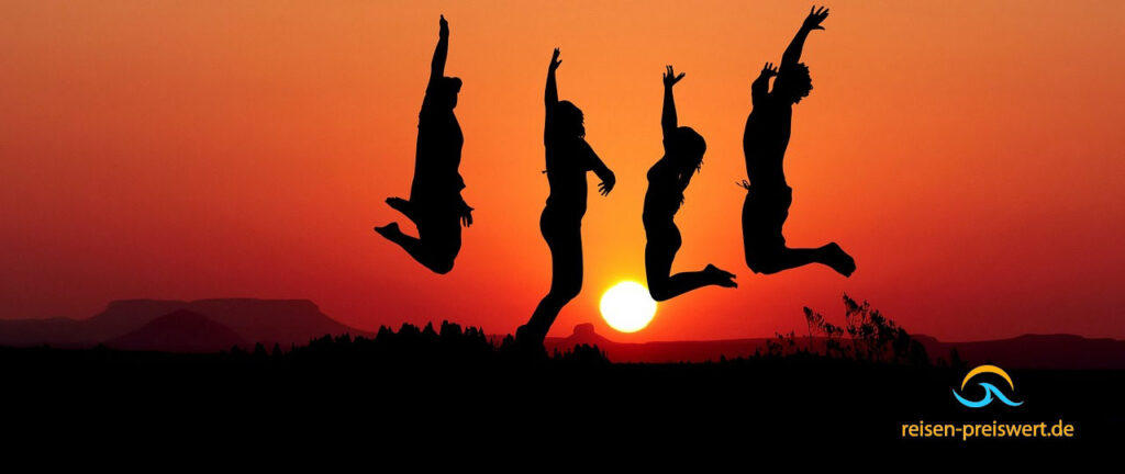 Vier Personen springen in die Luft. Im Hintergrund ist der Sonnenuntergang