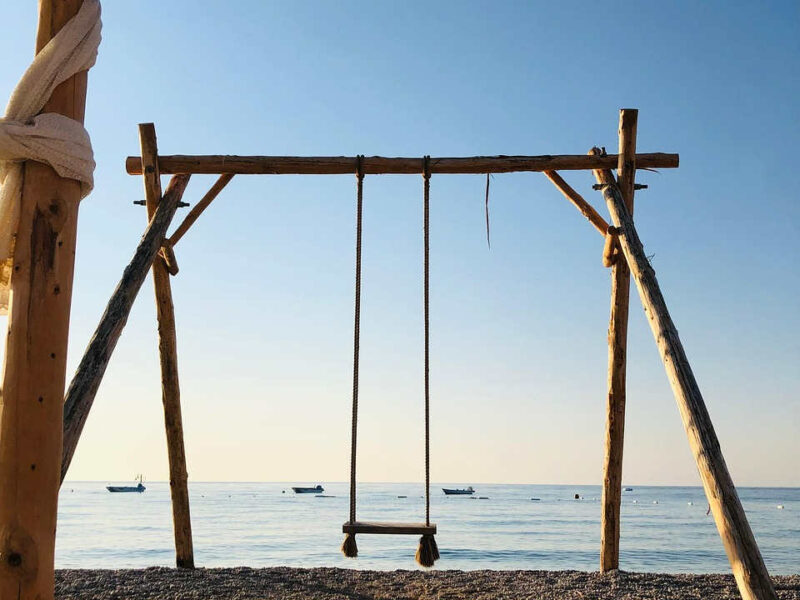 Eine Schaukel am feinen Sandstrand mit Blick auf das Meer in der Abenddämmerung