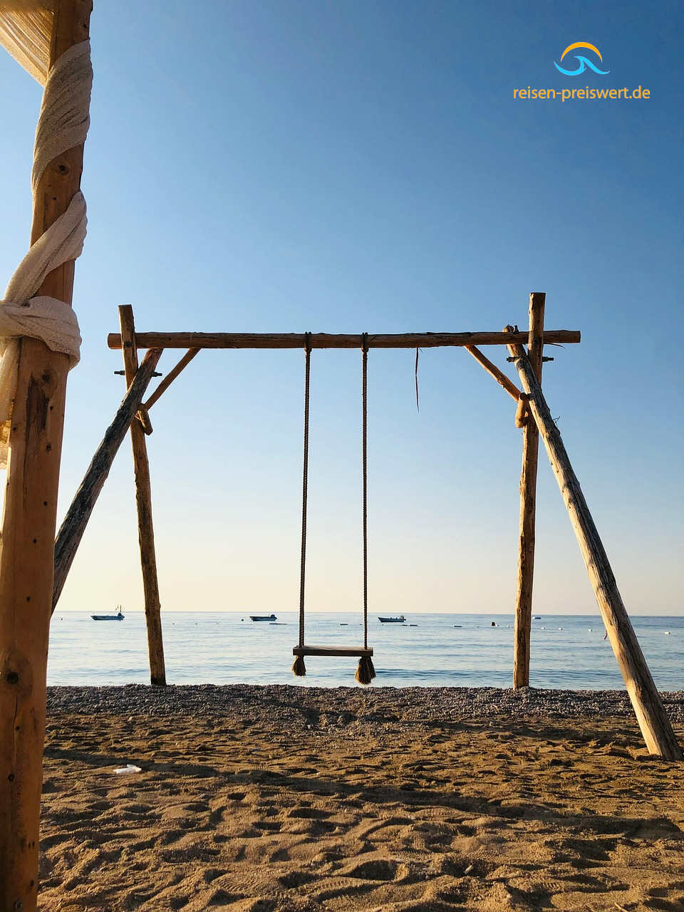 Eine Schaukel am feinen Sandstrand mit Blick auf das Meer in der Abenddämmerung